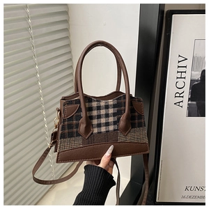 Detail van vintage geruite crossbodytas van bruin leer met ronde handvatten