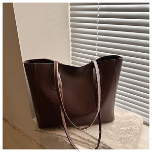Detail view of a large brown tote bag on a window sill with soft lighting shadows