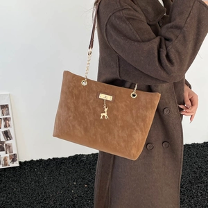 Brown frosted leather tote bag with deer charm and gold chain strap on model