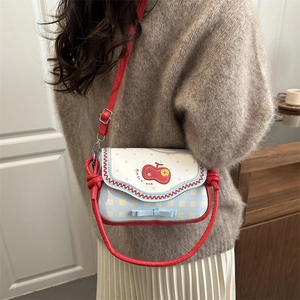 Women's plaid crossbody bag with apple embroidery and bow detail shown on a model