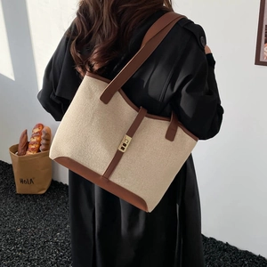 Fashionable beige canvas tote with brown leather trim shown on model back view