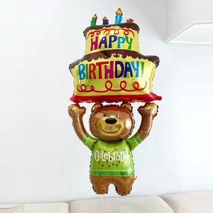 Detail of a brown bear foil balloon holding a yellow layered birthday cake decoration