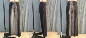 Detail view of baggy black jeans with metallic silver coating and vintage wash effect