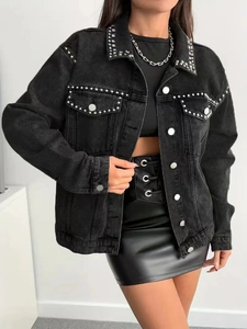 Detail of silver rivets on black denim jacket collar and pockets with metal buttons