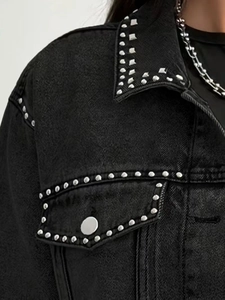 Detail of black denim jacket showing silver stud rivets and premium twill texture