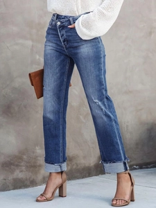 Vue détaillée de la taille haute croisée et de la texture vieillie du jean bleu droit
