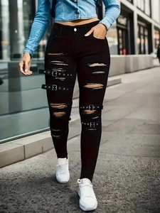Détail d'un jean skinny noir avec de grandes déchirures et des boucles métalliques