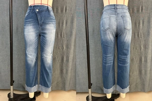 Détail de jean taille haute avec taille croisée asymétrique et revers à bords francs