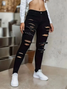 Détail du jean skinny noir taille haute déchiré avec boucles et œillets métalliques