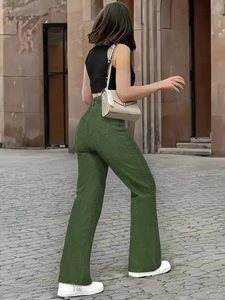 Outdoor street view of dark green high-waisted flared jeans from a back-side angle
