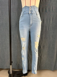 Detail of high-waist jeans featuring three-button closure and distressed ripped denim fabric