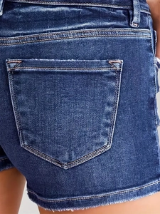 Close-up of back pocket details and distressed raw hem on vintage blue denim shorts
