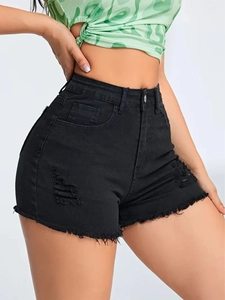 Detail of black distressed denim shorts featuring ripped elements and raw frayed hems