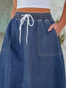 Détail de la taille élastique à cordon et des grandes poches sur la jupe en jean bleu