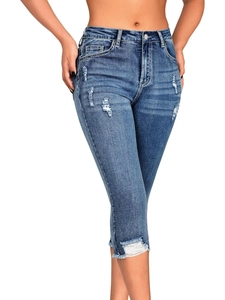 Close-up of distressed denim capri pants featuring ripped knees and frayed edges