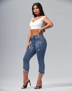 Detail of slim fit distressed denim shorts with ripped accents and raw hems on model
