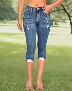 Close-up of distressed denim capri pants featuring frayed hems and vintage rip details