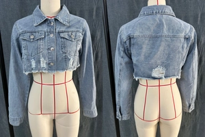 Dettaglio giacca di jeans corta azzurra con orlo sfilacciato e strappi sulla schiena