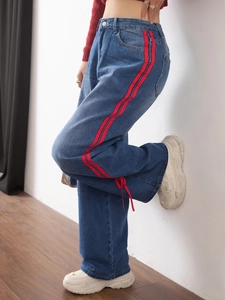 Detail of red side stripes and stylish bow tie decoration on wide-leg denim jeans