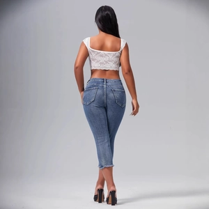 Slim fit denim capri pants with frayed hems and lace crop top in trendy street style
