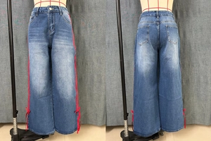 Detail of blue wide-leg denim jeans featuring red side ribbon criss-cross lacing