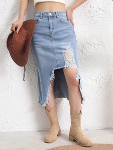 Detail of distressed denim skirt featuring irregular frayed hem and ripped bohemian texture