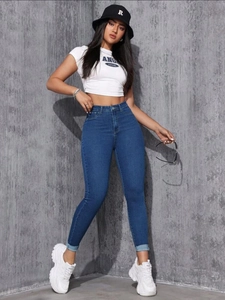 Détail du jean slim bleu taille haute avec texture délavée et revers élégants aux pieds