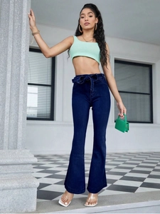 Deep blue high-waisted flared jeans with a matching fabric bow belt in a stylish outdoor setting
