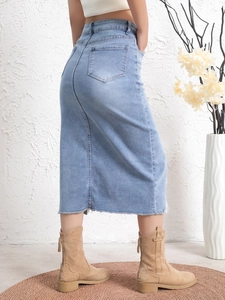 Detail shot of the back pockets and raw hem edge on the light blue denim midi skirt
