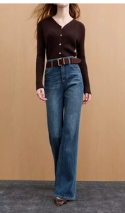 Close-up of retro blue high-waist flared jeans with a belt and brown knit sweater