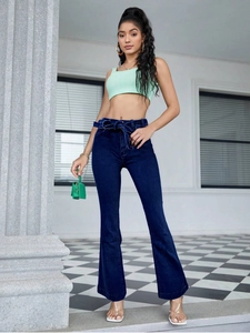 Detail of high-waisted dark blue flare jeans featuring a stylish self-tie fabric belt