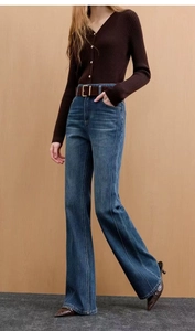 Detail of high waist flared jeans in dark blue with center crease and metal buckle belt