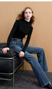 Detail of high waist flared jeans with center pleats and a thin black leather belt