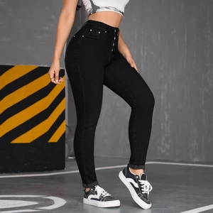 Women's high waist skinny black jeans with button fly and cuffed hem in urban setting
