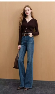 Detail of high-waisted blue flare jeans with vertical seam and brown ribbed knit cardigan