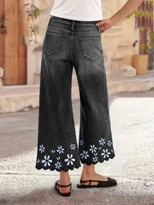 Women black wide leg cropped jeans featuring white floral embroidery and scalloped hem