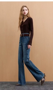 Detail view of high-waist flared jeans paired with a brown knit cardigan and belt