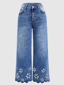Detail of scalloped hem with white daisy embroidery on blue high-waist jeans
