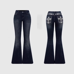 Detail of white cross embroidery on back pockets of dark blue flared denim jeans
