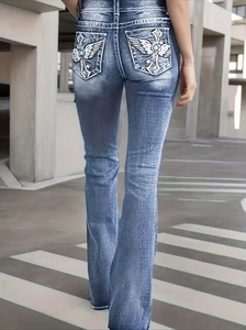 Women's vintage flared jeans featuring white wing and cross embroidery on back pockets