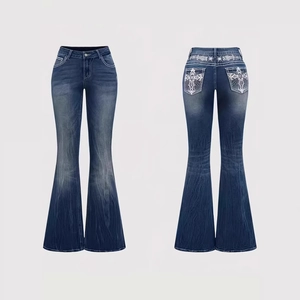 Detail of high waist flare jeans featuring cross embroidery and washed blue denim texture