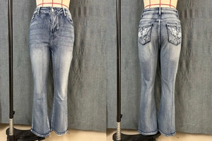 Detail of high waist flared jeans with cross and wing embroidery on back pockets