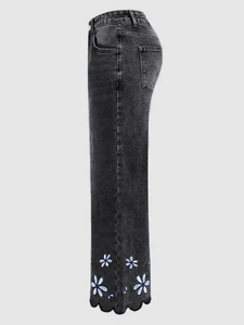 Detailed view of daisy embroidery and scalloped edges on charcoal denim jeans cuffs