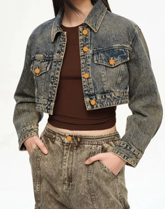 Detail of vintage acid wash blue denim jacket with orange buttons and chest pockets