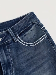 Detail of blue denim fabric showing white contrast stitching and washed texture