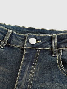 Detailed view of dark blue flared jeans featuring a silver button and denim texture