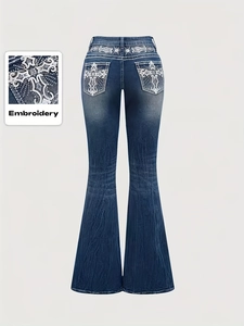 Detail of white cross embroidery and baroque patterns on back pockets of flared jeans
