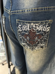 Detail view of retro embroidery and Lost Souls lettering on flare denim jeans back pocket