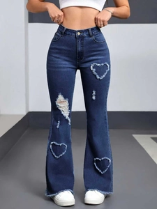 Detail of high waisted flared jeans featuring heart shaped distressed cutouts and frayed edges