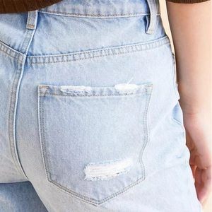 Vue détaillée du jean taille haute bleu clair montrant la texture usée de la poche arrière